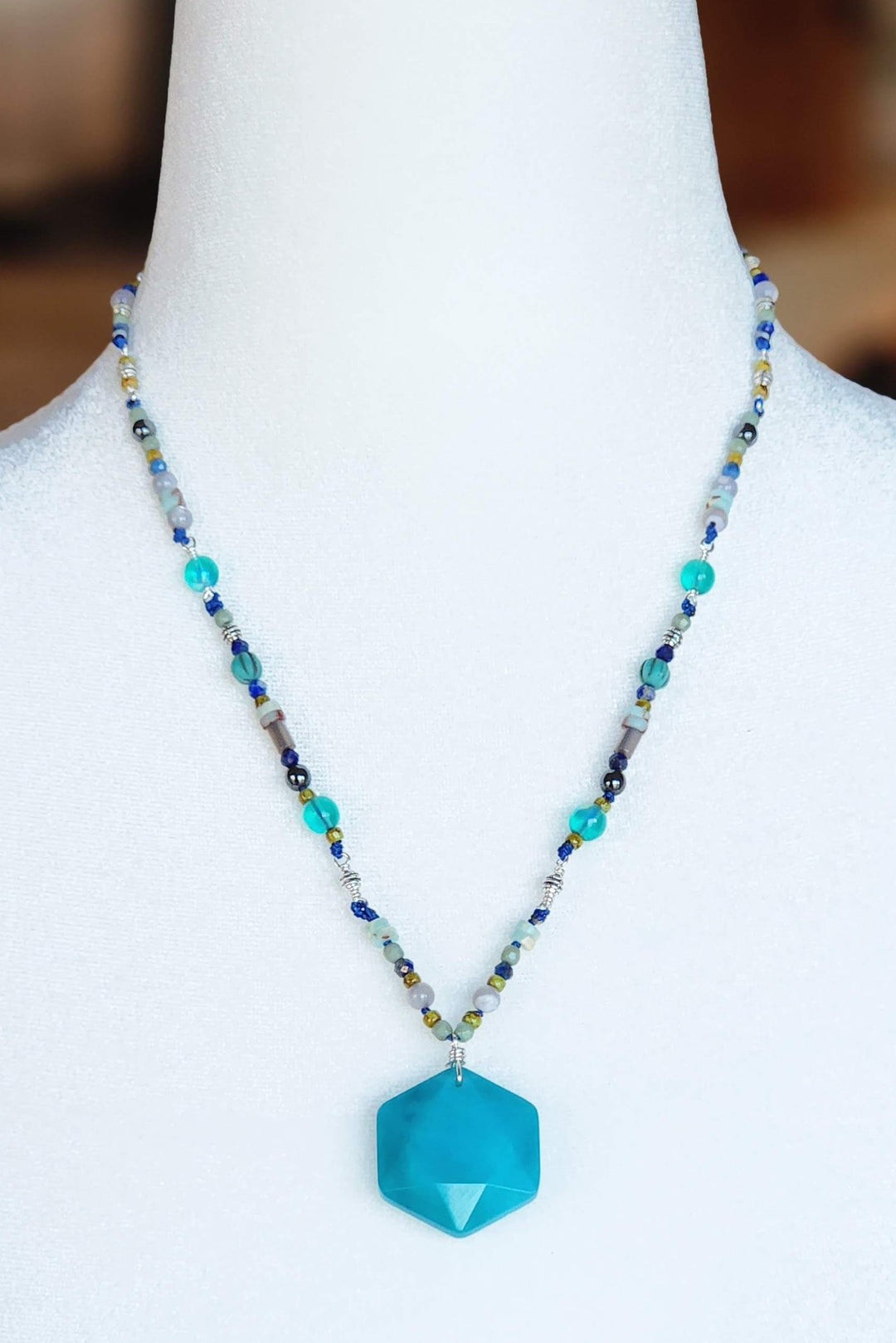 This is a photo displaying the Dolphin Necklace on a white mannequin bust.