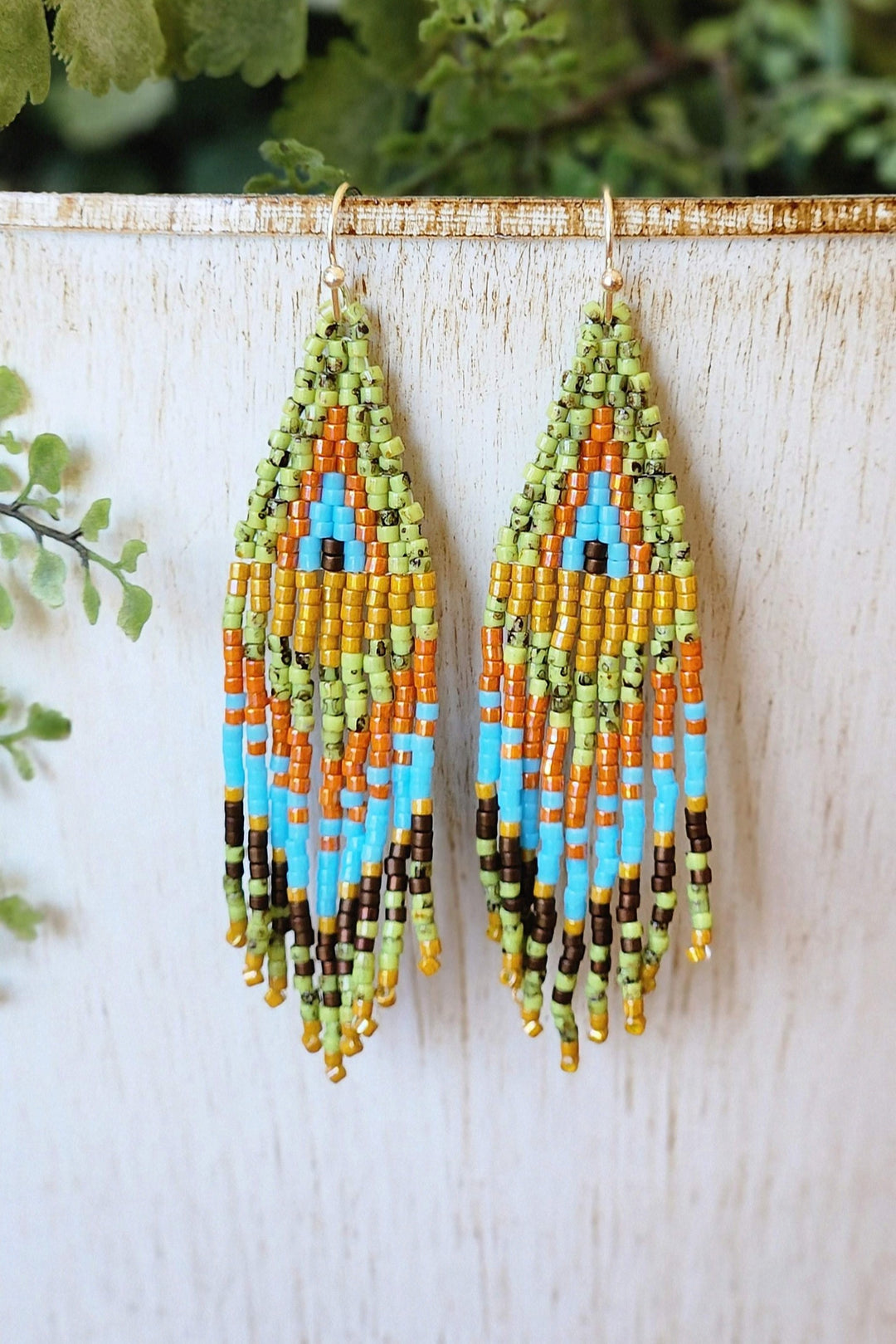 This photo showcases the Bright Green, Vibrant Orange, Rich Yellow, Cool Blue, and Dark Brown color pallet of the Dragonfly Eye Seed Bead Earrings.