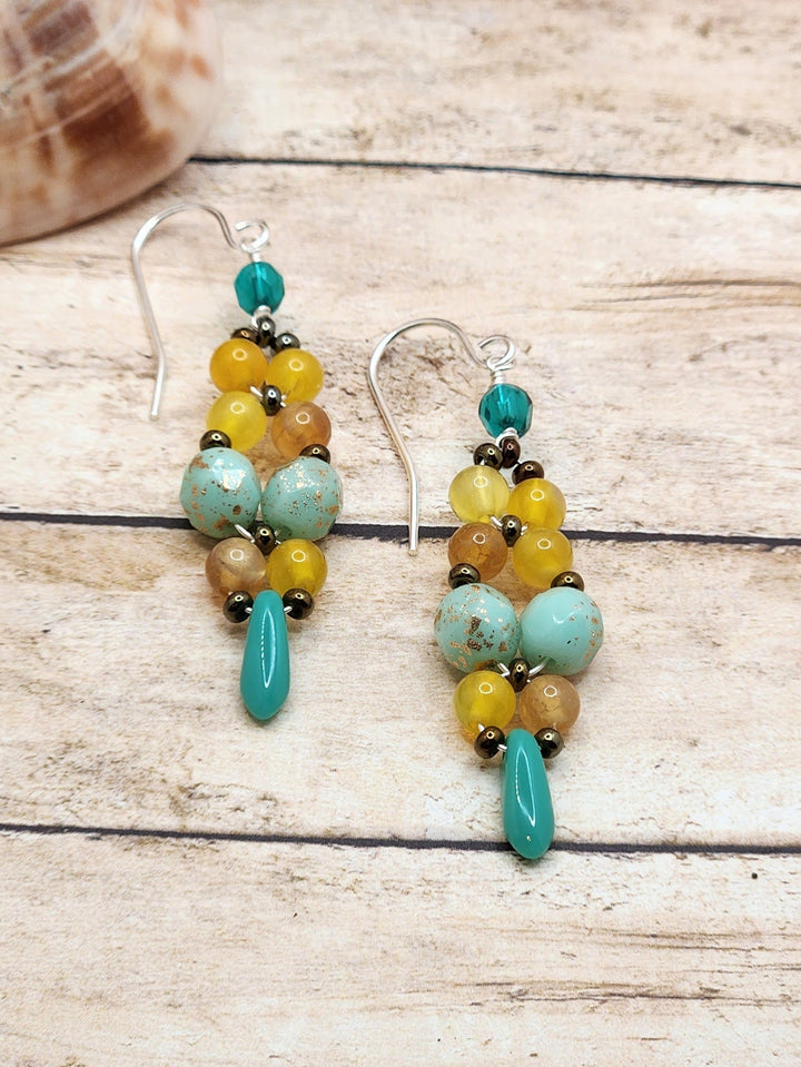 This close-up photo of the Land, Sea, and Sky Earrings showcases the yellow, blue, and brown color palette of these earrings.