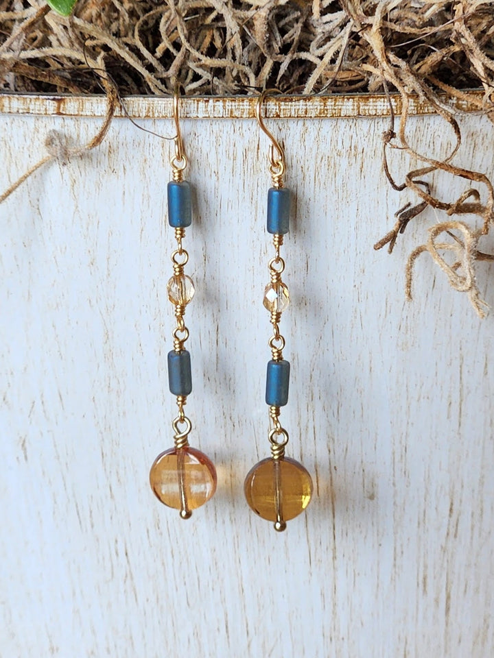 This photo shows the intricate handmade wire connections that makeup these earrings displayed against a white pottery background. 