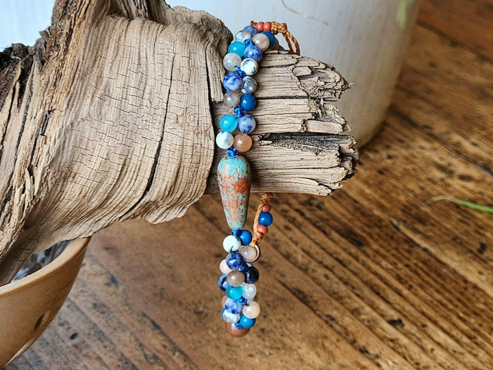 This is a photo displaying the Blue Blue in Flight Bracelet on a piece of wood wich compliments the natural feel of 5he piece.