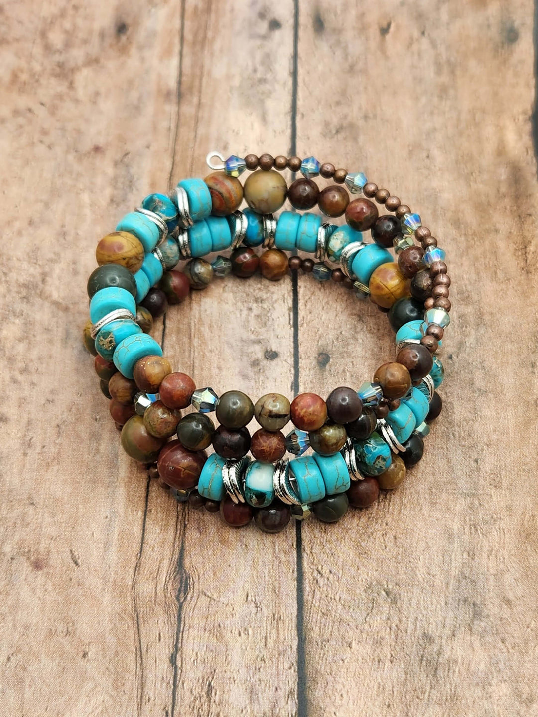 This photo of the Grand Canyon Memory Wire Bracelet shows the many shapes, sizes and textures with blue, brown, tan, and green beads that makeup this bracelet.