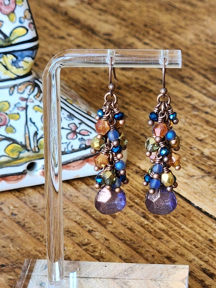 This is a photo displaying the Grape Cluster Earrings on a clear display stand. 