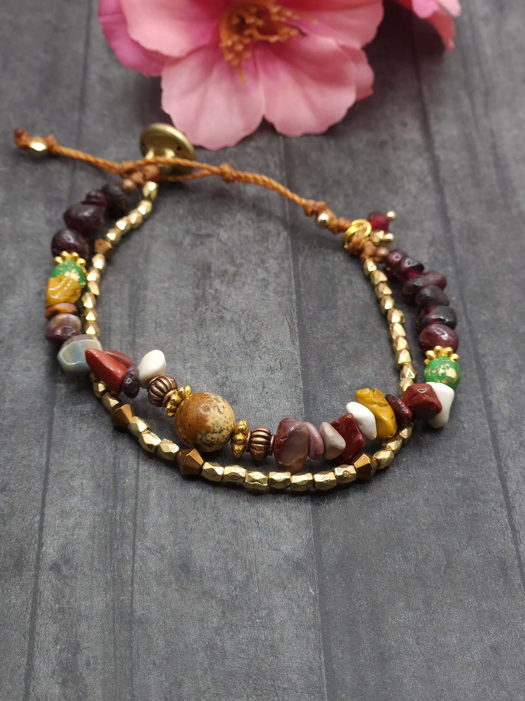 This photo of the Rainbow Mountains Bracelet shows a row of brown, green, white, yellow, red beads varied in a row, with a second row of gold beads.