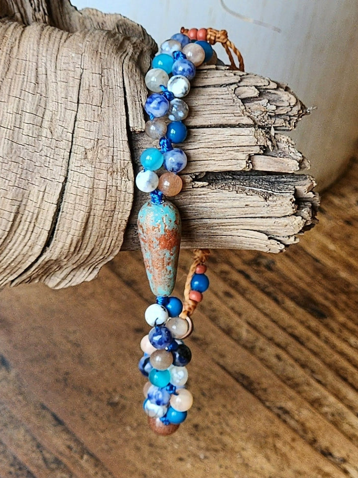 This is a photo of the Blue Brid in Flight Bracelet displayed hanging on a piece of wood.  