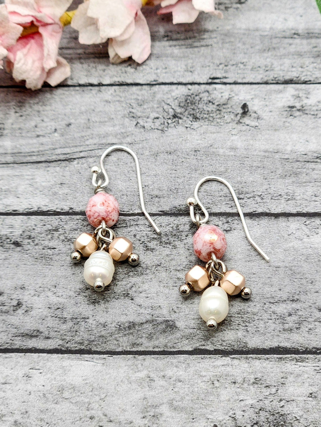 In this close-up photo of the Cherry Blossum earrings, the soft pink of the hematite blends with the mottled pinks of the Czech Glass fire-polished beads. A single pearl dangles from each earring.  